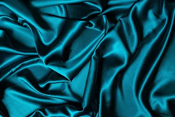 Teal silk fabric showing its smooth surface and drape
