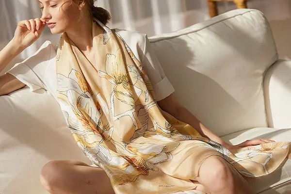 Woman wearing a long cream printed scarf with a light jacket