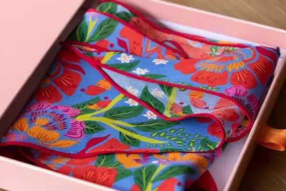 Bright floral printed scarf folded inside a pink gift box