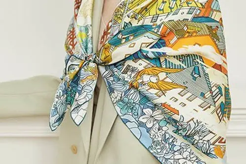 Printed square silk scarf tied over the shoulders with the border visible