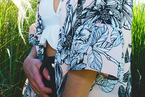 Black floral line pattern printed across a light kimono-style garment worn outdoors