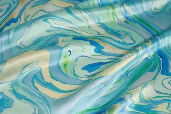 Blue and green abstract pattern printed across softly folded silk