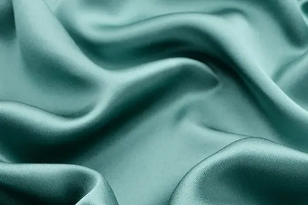 Teal silk satin fabric showing a smooth lustrous surface and fluid drape