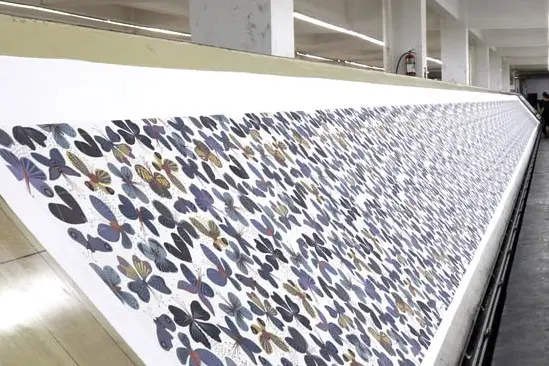 Long screen-printing table carrying a repeating butterfly fabric pattern