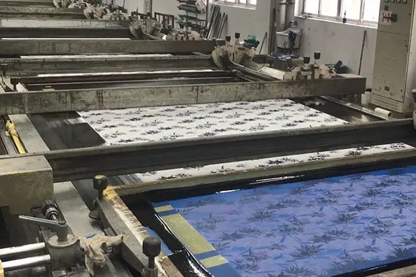 Patterned fabric moving through a machine screen-printing line