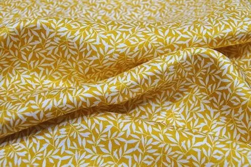 Mustard leaf pattern printed across folded silk twill fabric