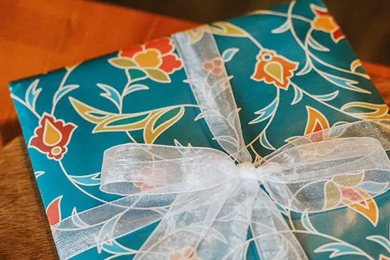 Printed scarf folded as a gift and finished with sheer ribbon