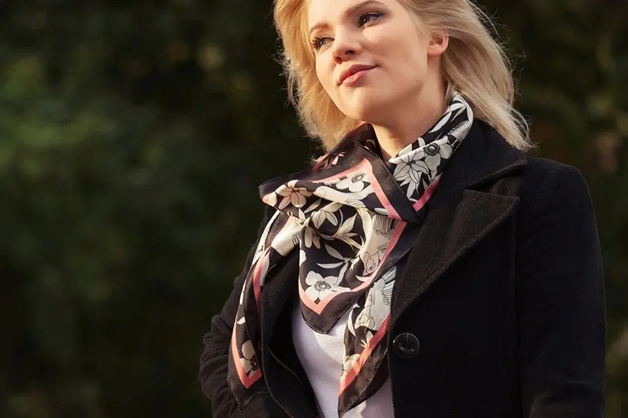 Printed square silk scarf layered over a dark winter coat