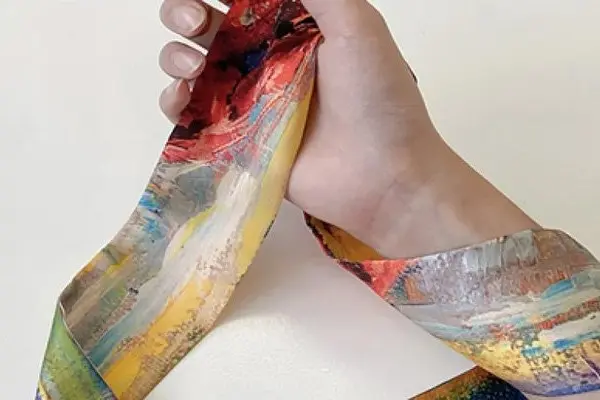 Narrow printed twilly tied around the wrist to show an accessory-scale scarf format