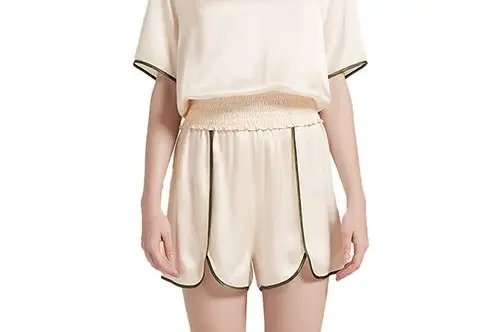 Ivory silk pajama shorts showing a gathered elastic waist and contrast piping