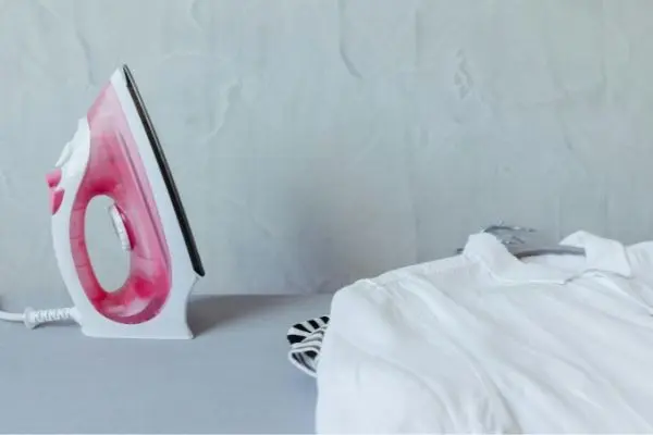 Creased white garment laid beside an iron before wrinkle removal