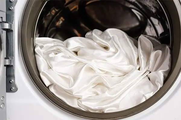 White silk pillowcase fabric inside a washing machine, a method that should only follow the care label