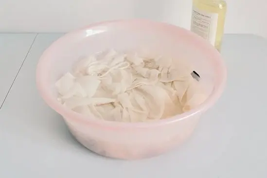 Light-colored silk scarf soaking gently in a clean wash basin