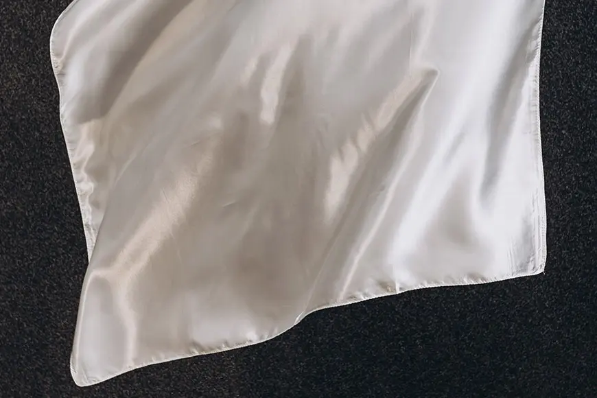 White silk scarf laid flat to show its smooth surface and finished edge